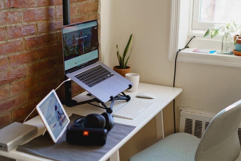 Home office setup in a small apartment with a laptop on a laptop stand, ipad set up as a sidecar, apple magic keyboard and ikea desk chair